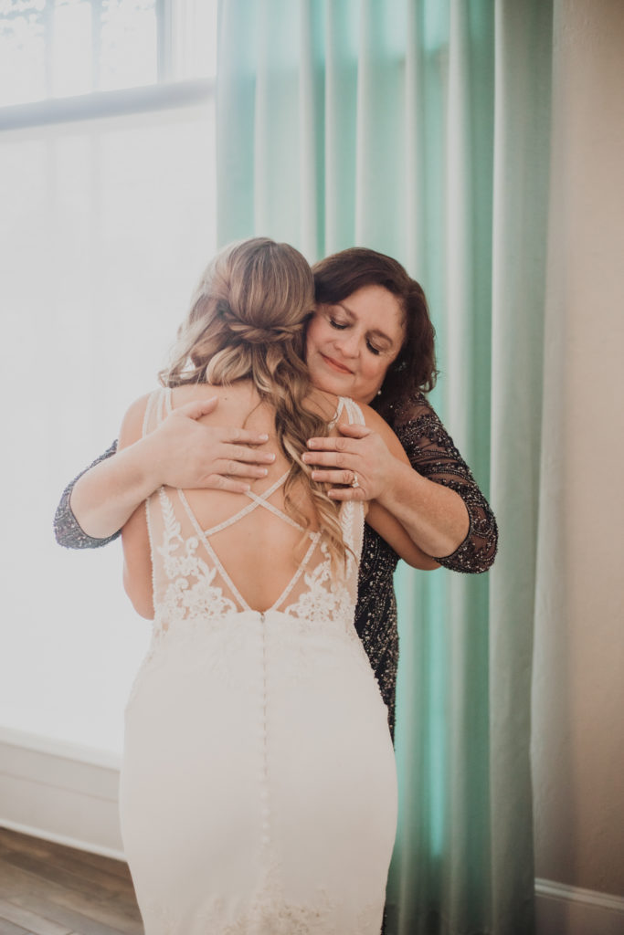 mom and bride hugging white room